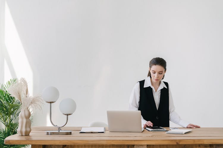 Woman In Black Vest Using A Tablet On Wooden Table