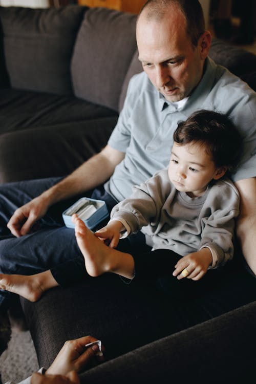 A Father Sitting With His Child On A Sofa