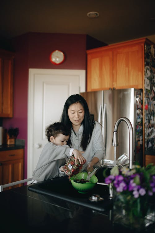 Mother And Child Putting Strawberries In A Bowl