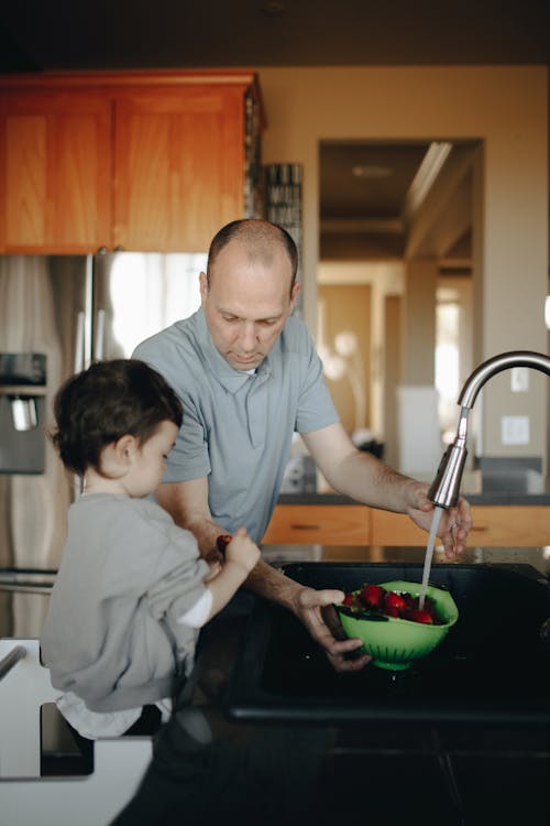 Father And Child Washing A Bowl Of Strawberries