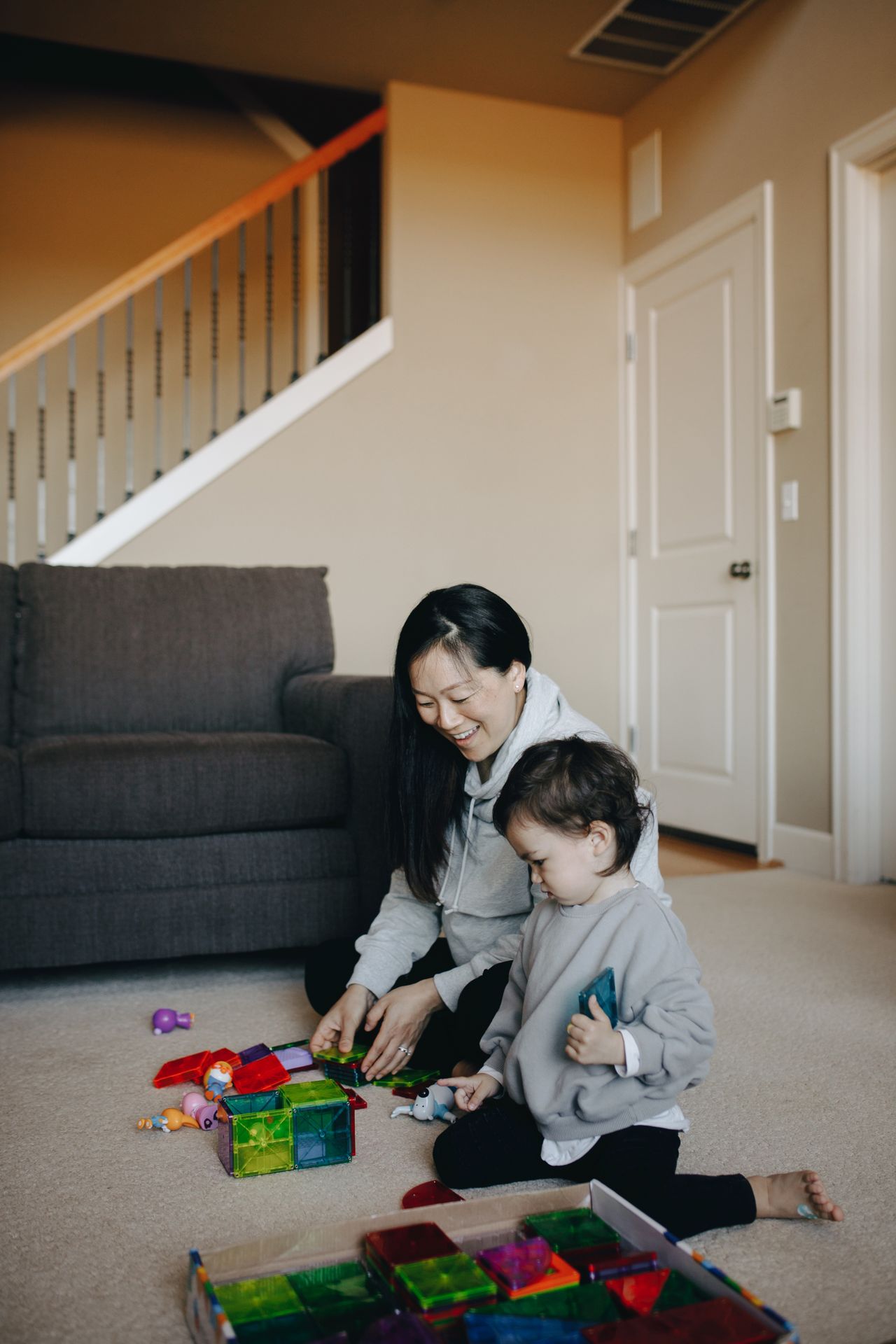 A mother and her young child play with colorful toys indoors, capturing a warm family moment.