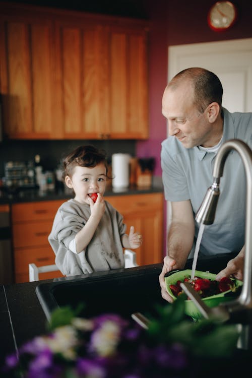 A Child Eating And Father Washing Bowl Of Strawberrries 