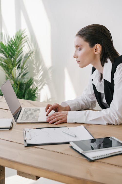 
A Woman Wearing a White Long Sleeved Shirt Using a Laptop