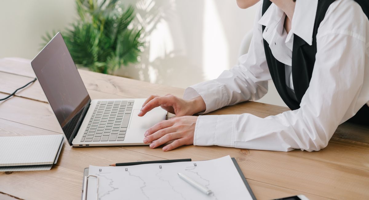 Woman typing on a laptop beside paperwork