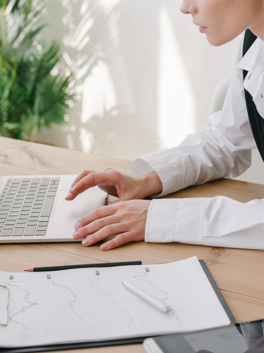 Woman typing on a laptop beside paperwork