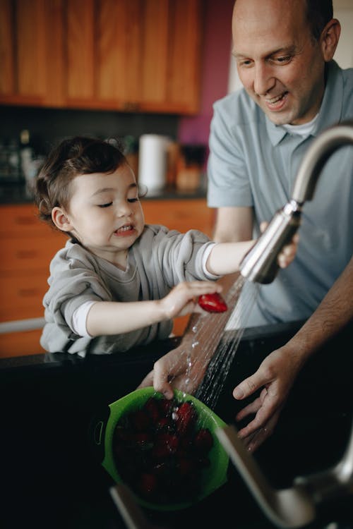 Father And Child Washing Strawberries In A Bowl