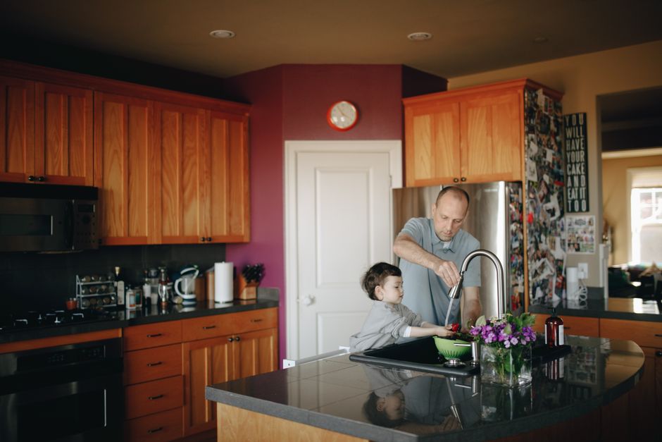 Father and child wash fruit together in a cozy kitchen, highlighting family bonding and love.