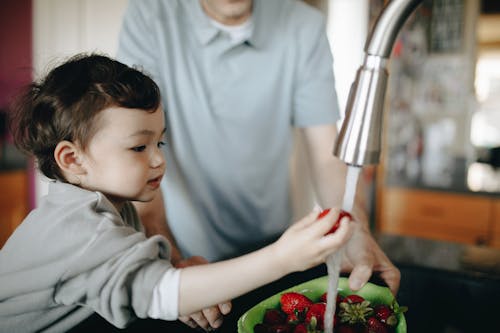 A Child Washing Strawberries In A Bowl