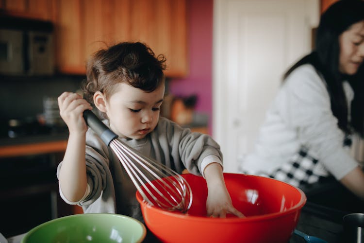 A Child Baking In The Kitchen With Her Mom