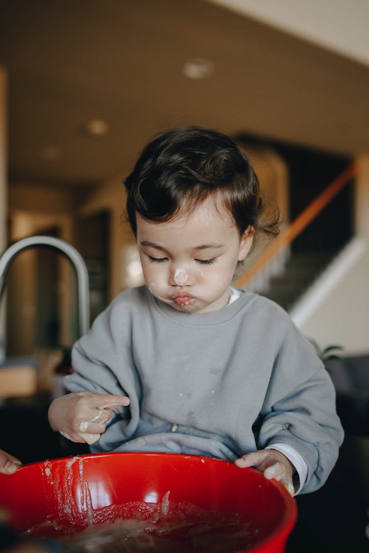 A Child Playing With Mixture On A Bowl