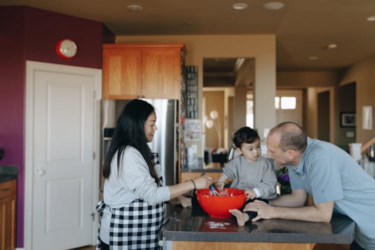 A Couple Cooking In The Kitchen With Their Child