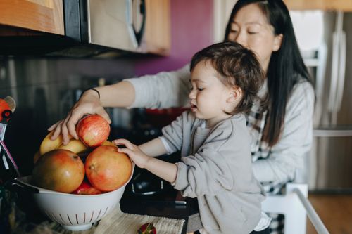 Free A mother and child enjoy selecting fresh apples together in the kitchen. Stock Photo