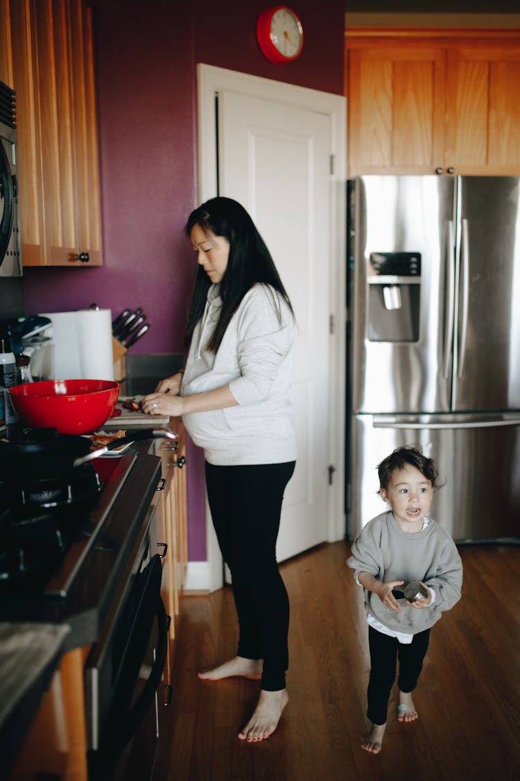 Woman Doing Chores In The Kitchen With Her Child