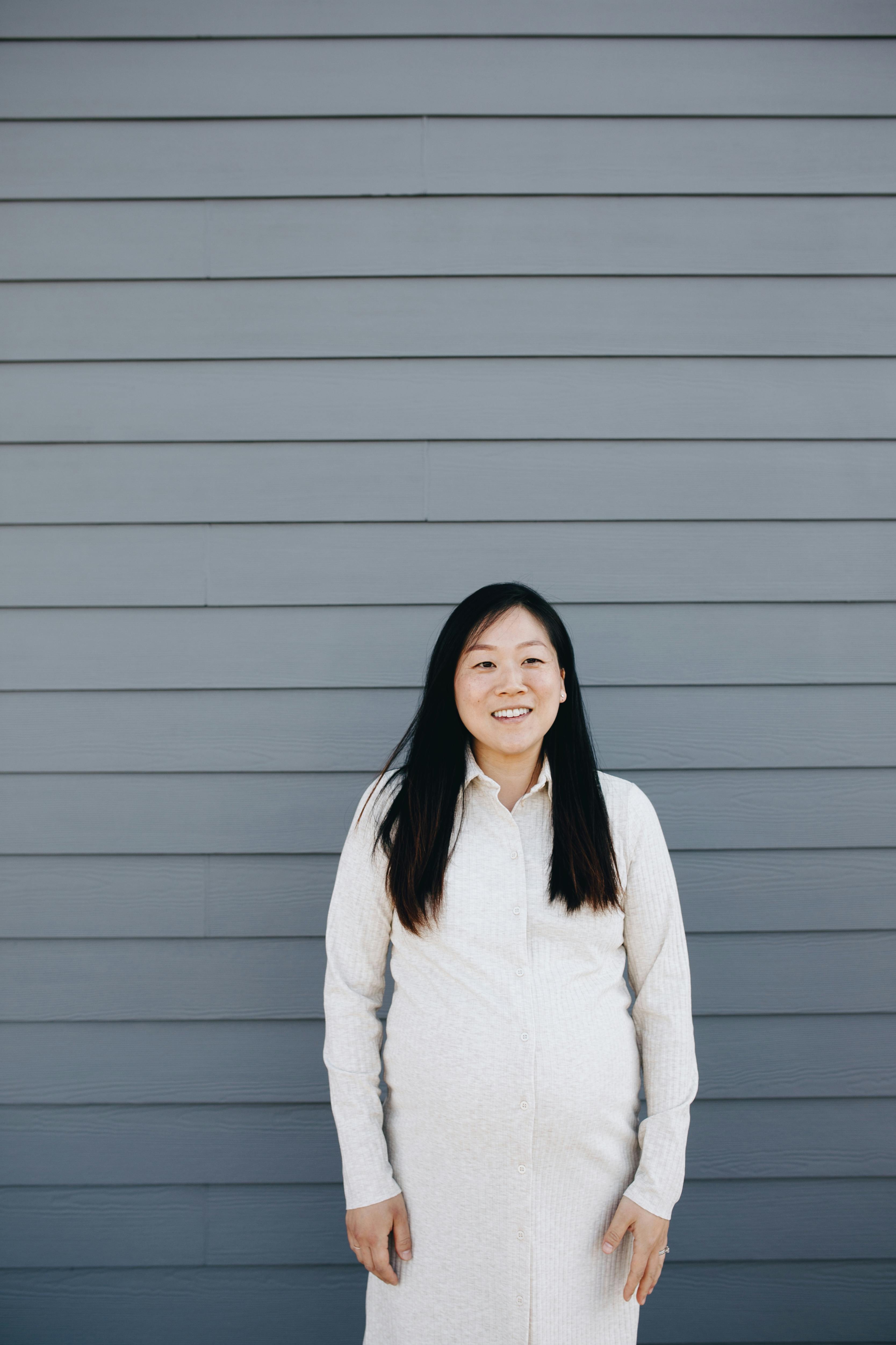 pregnant woman standing beside a gray wall