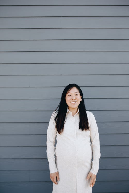 Pregnant Woman Standing Beside A Gray Wall