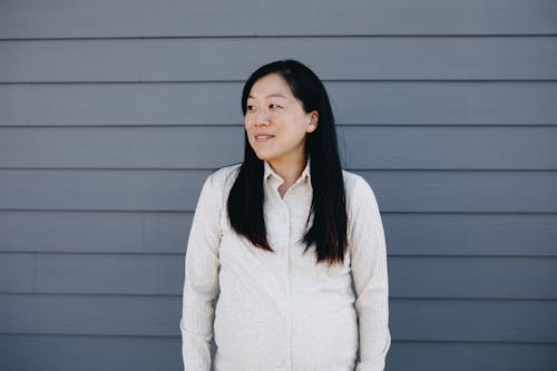 Woman Standing Beside A Gray Wall Looking Sideways