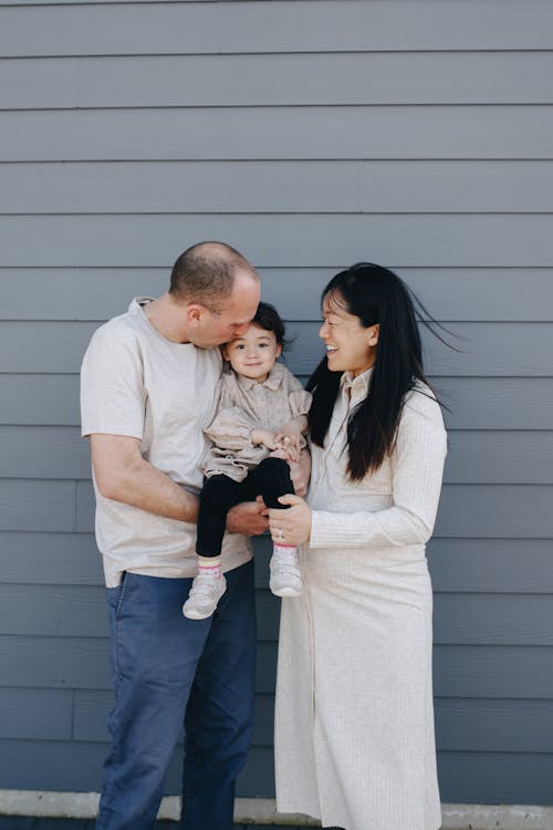 A Father Carrying And Kissing Her Daughter In The Forehead