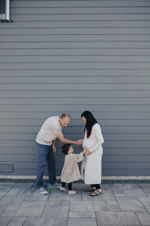 Father And Daughter Touching A Pregnant Mother's Tummy