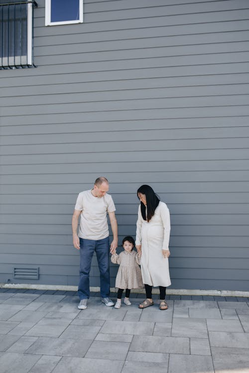 A Family Standing Beside A Gray Wall