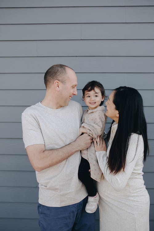Happy Family Standing Beside A Gray Wall