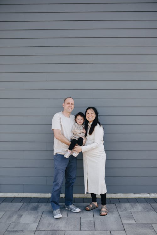 Happy Family Standing Near A Gray Wall