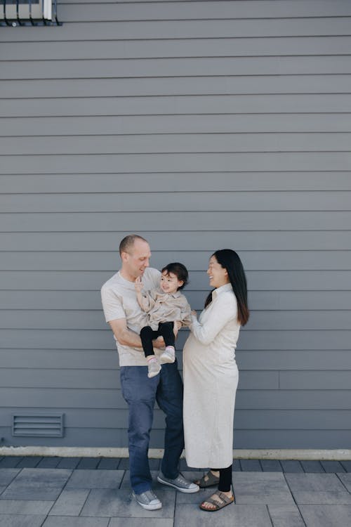 Happy Family Standing Beside A Gray Wall