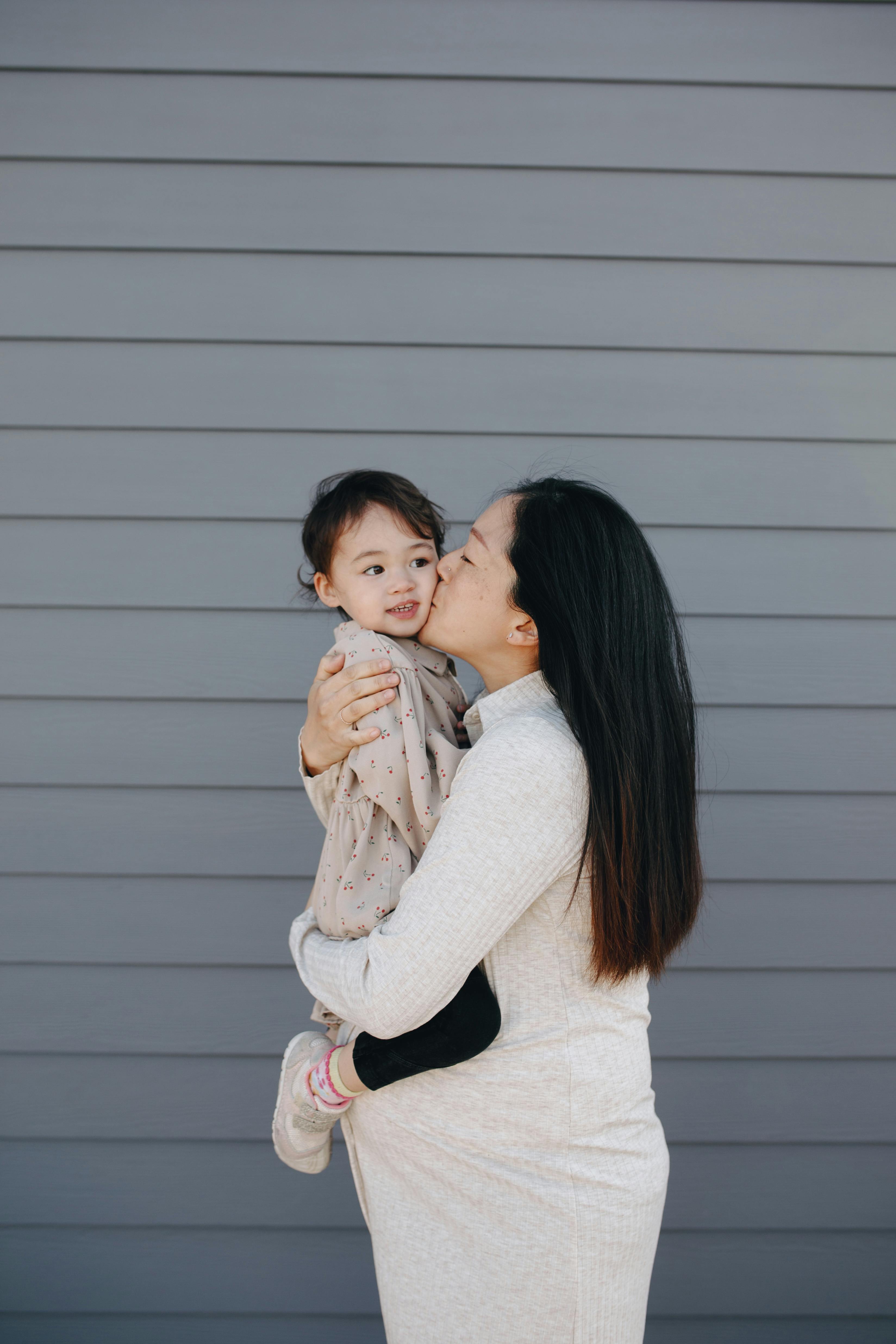 pregnant mother kissing her baby girl