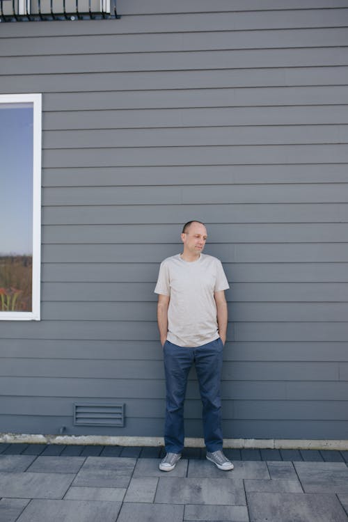 Man Standing Beside A Gray Wall