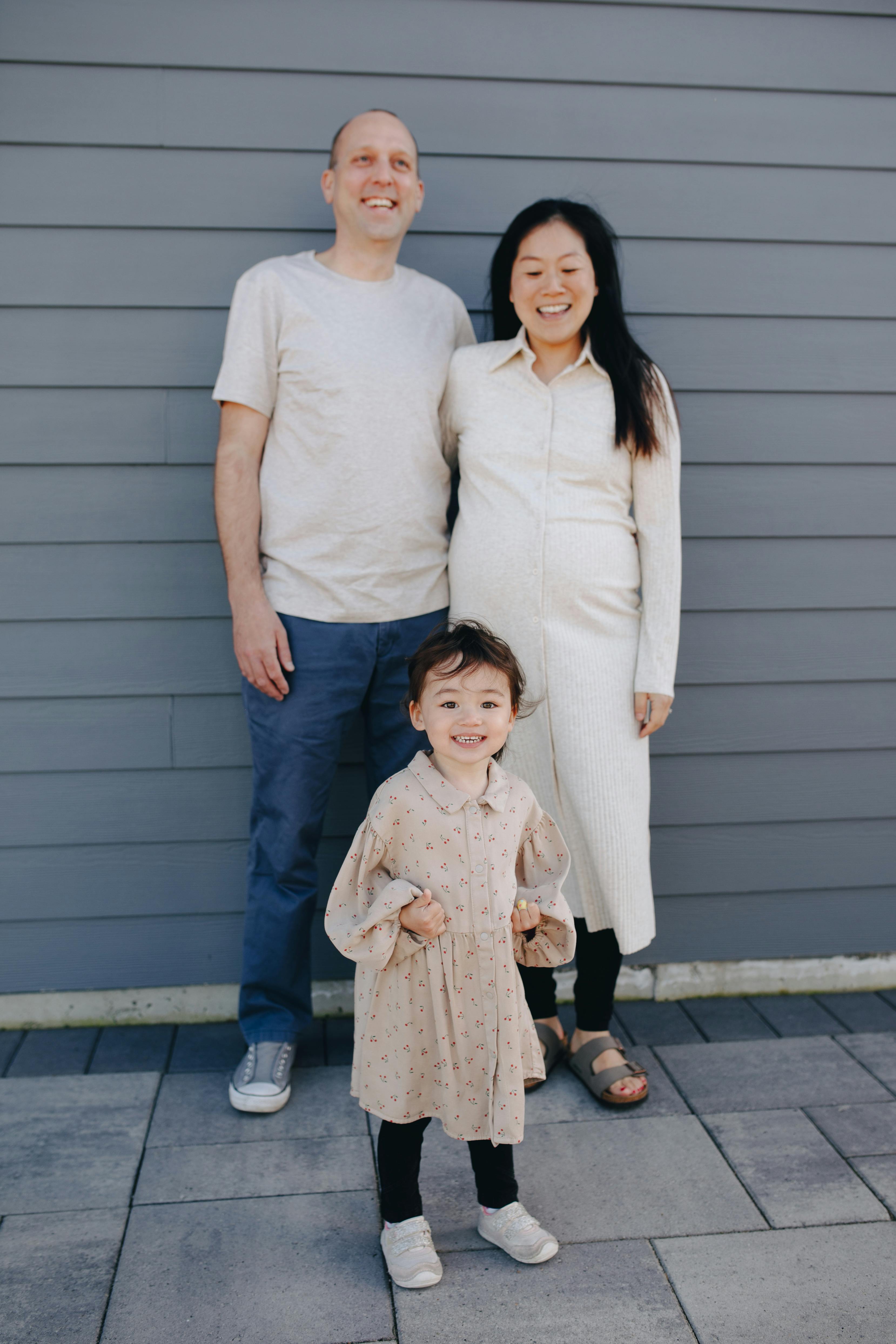 happy family standing near a gray wall