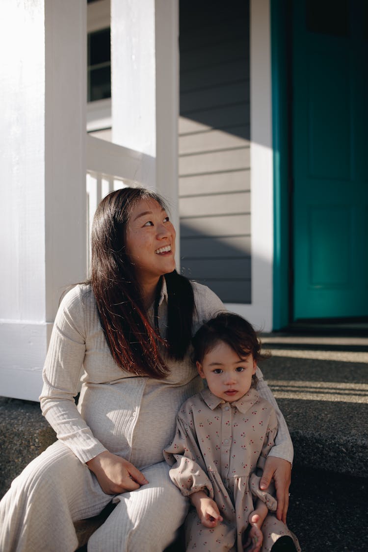 Mother And Her Child Sitting On The Steps To A Porch