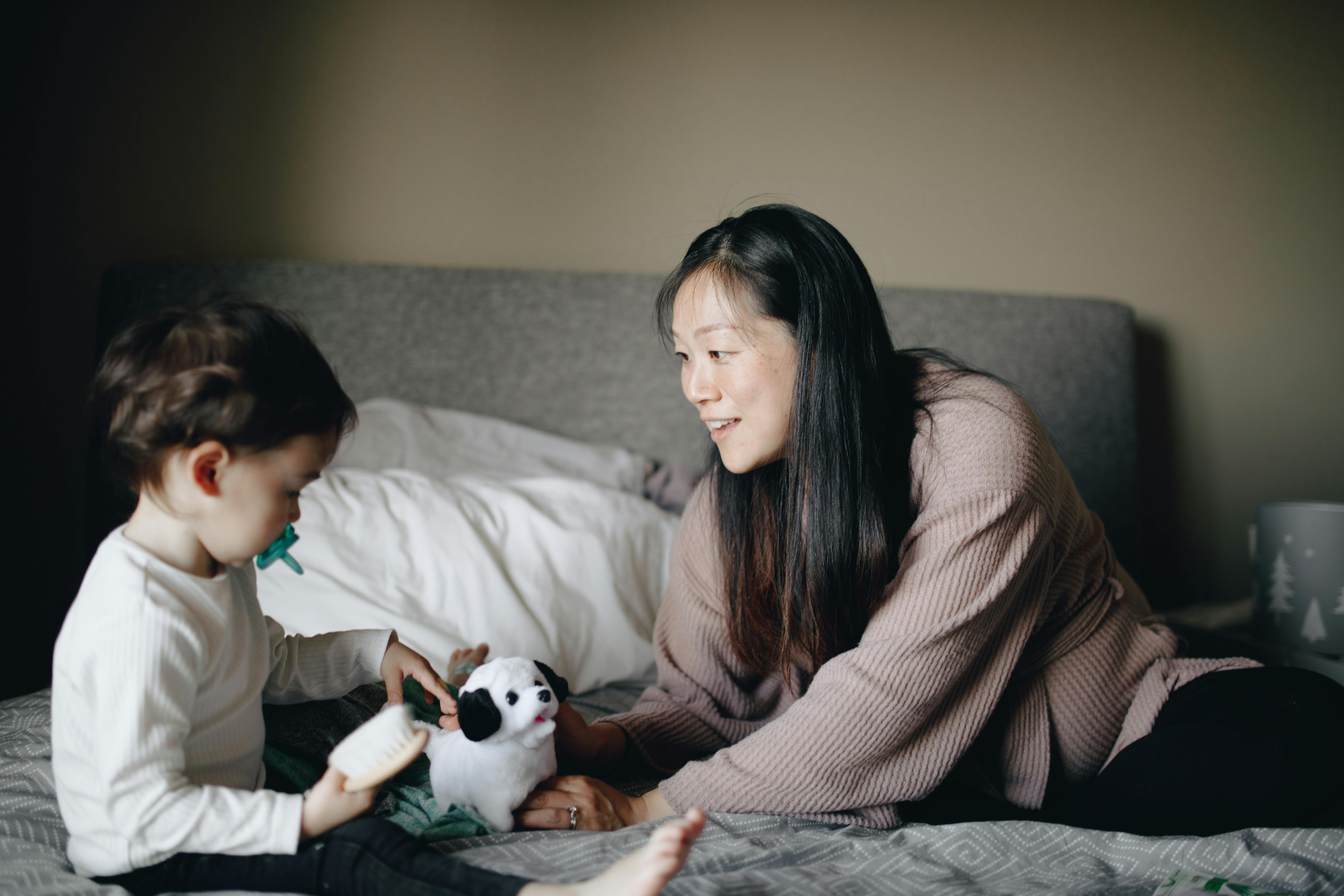 mother and baby playing with white and black dog plush toy