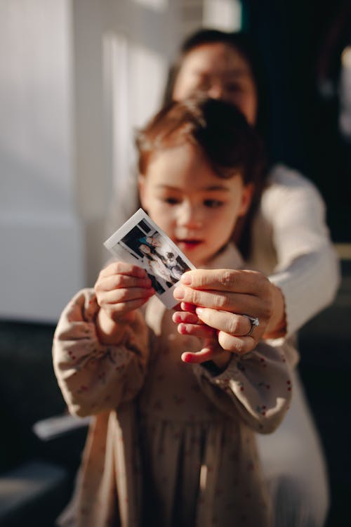 Mother And Child Holding An Instant Photo