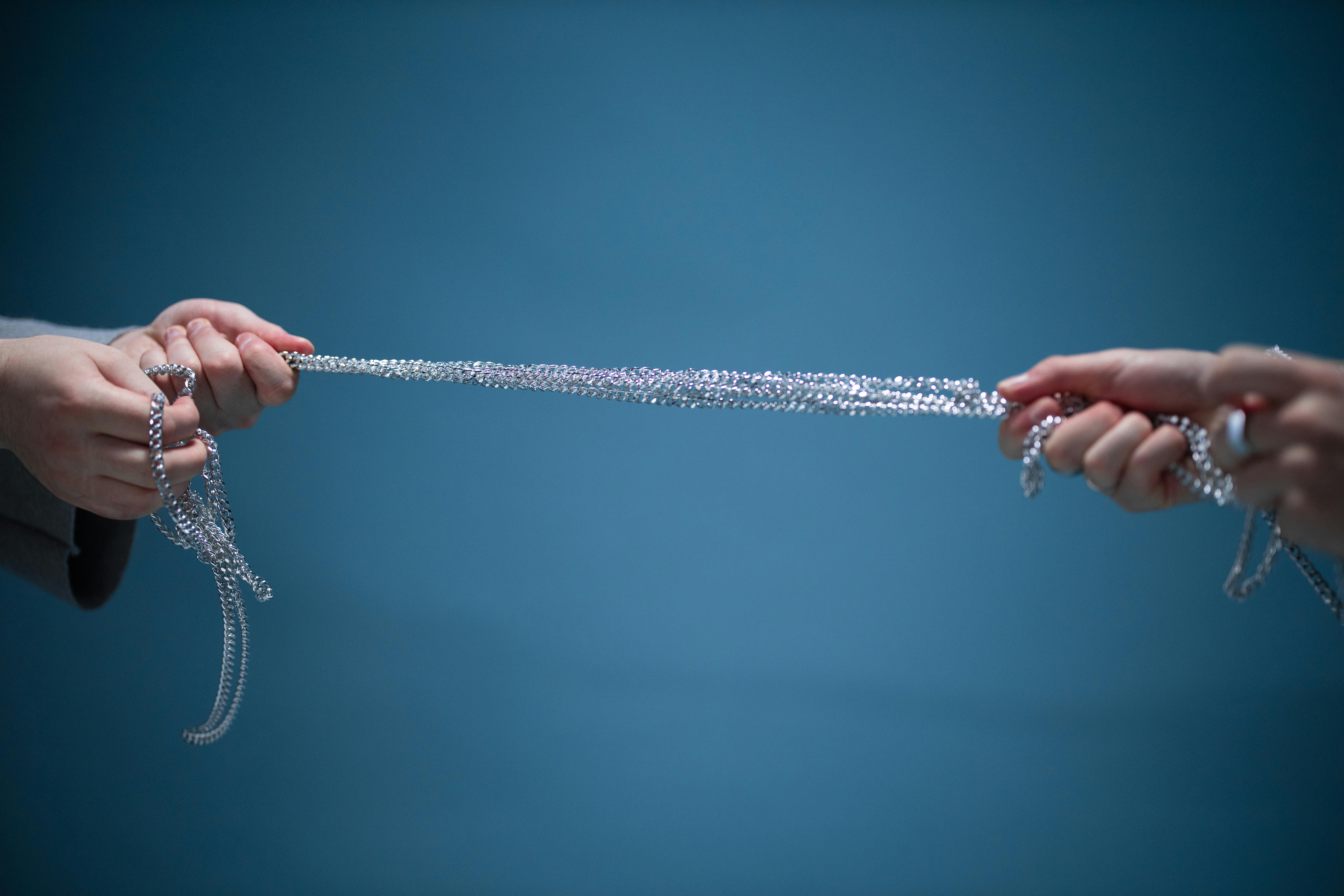 close up of hands pulling a silver chain from both sides