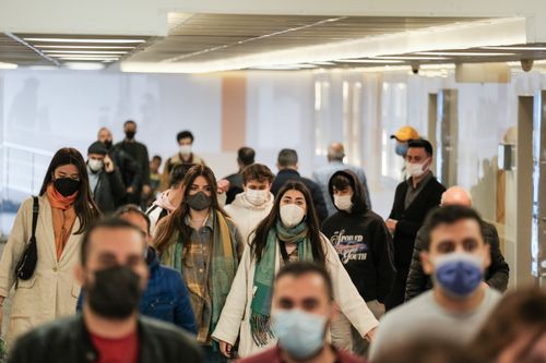 Free A diverse group of people wearing face masks walking indoors during the pandemic. Stock Photo