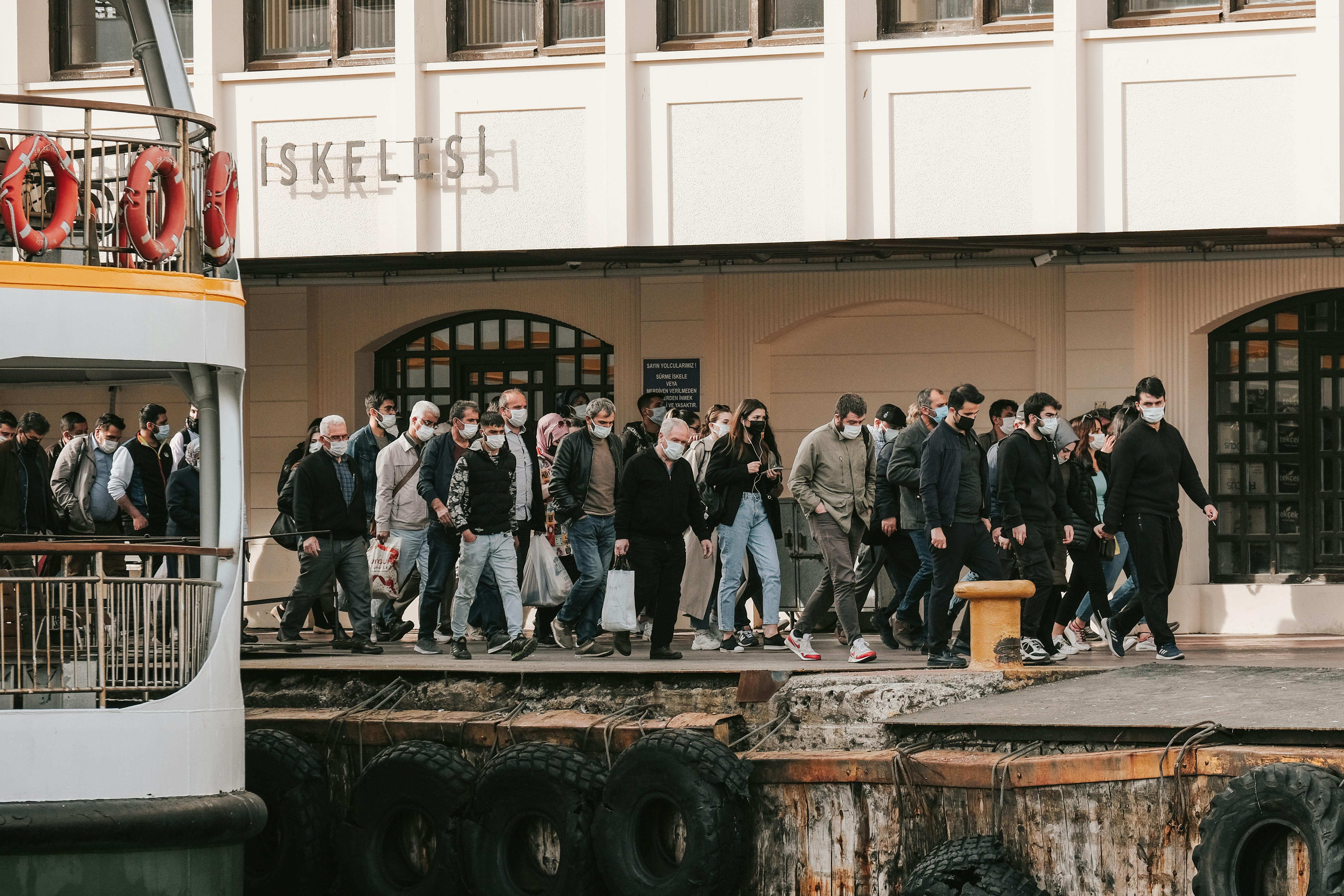 People wearing masks disembark a ferry at Istanbul's bustling ferry terminal.
