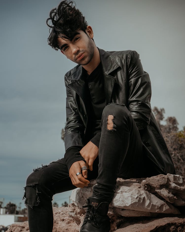 Man In Black Leather Jacket And Black Pants Sitting On Rock