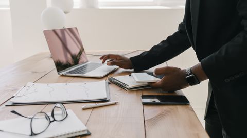 Professional workspace with a laptop, documents, and stationery on a wooden table.