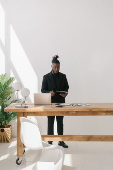 Businessman in black suit working with technology at a minimalist home office desk.