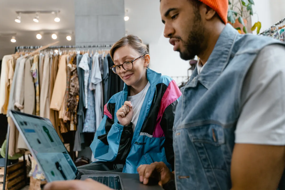 Two people looking at SEO optimization service options on a laptop in a shop.