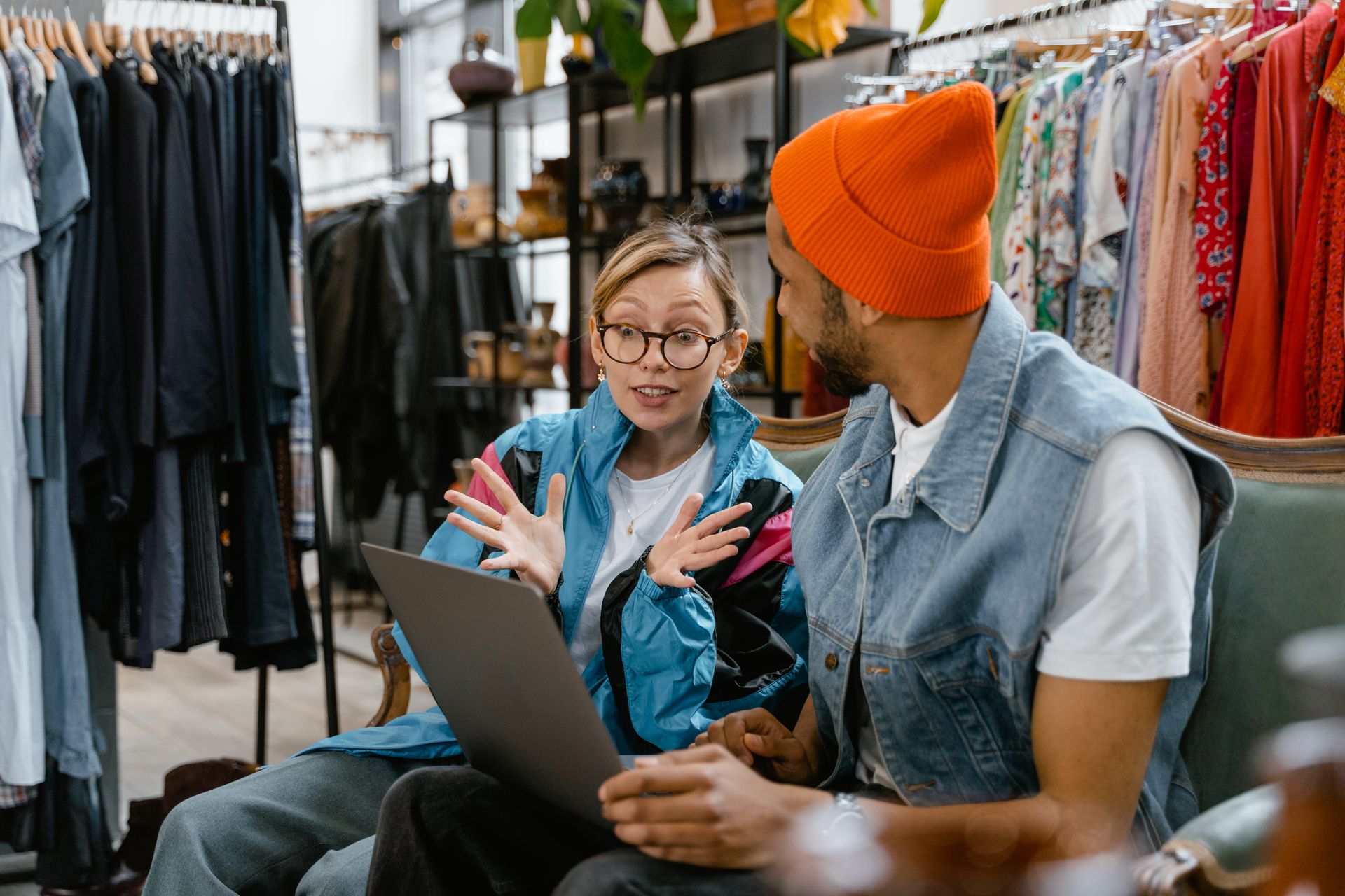 Two friends enjoy online shopping in a stylish clothing boutique.