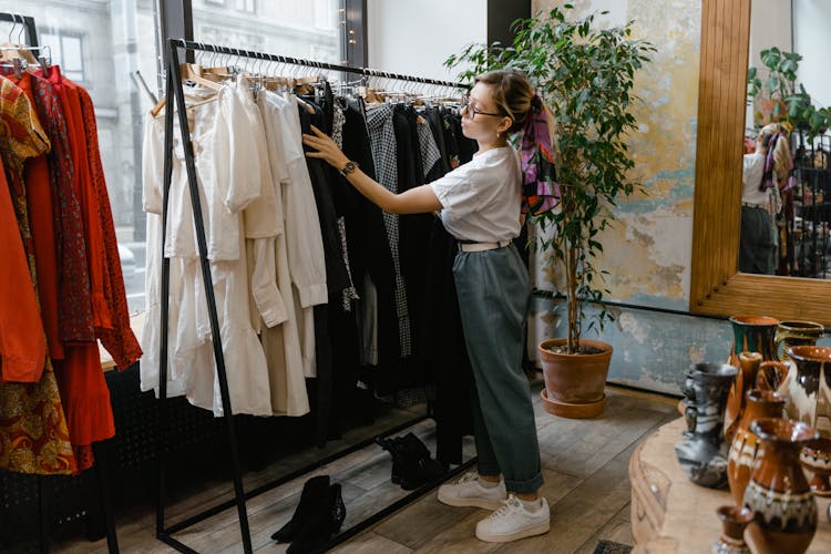 A Woman Looking At Clothes Hanging In The Rack