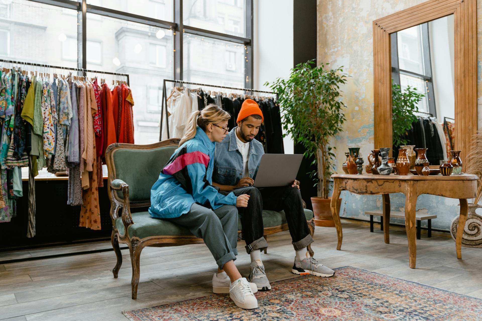 Two individuals collaborating on a laptop in a fashionable boutique setting.