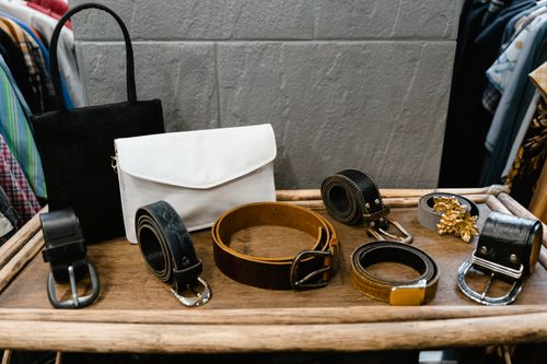 Free A collection of stylish belts and handbags displayed on a wooden rack in a fashion boutique. Stock Photo