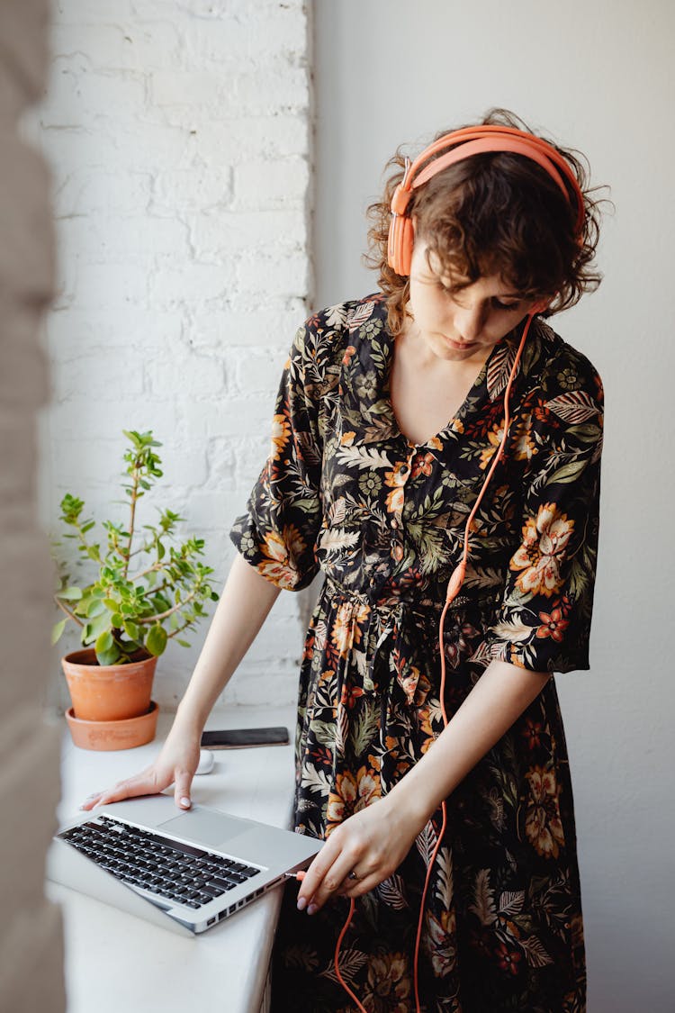 A Woman Hooking A Headphone Jack To A Laptop