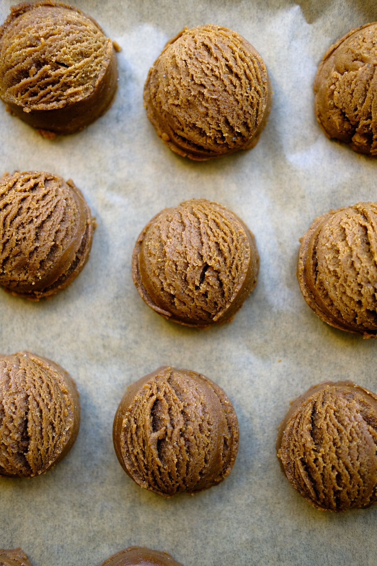 Rows of chocolate cookie dough balls on a parchment-lined baking sheet, ready to freeze or bake