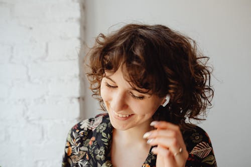 Free Close-Up Photo of a Woman with Curly Hair Wearing Airpods Stock Photo
