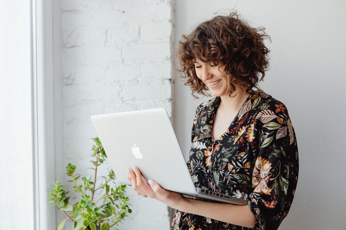 Free Woman in Floral Dress Holding a Laptop Stock Photo