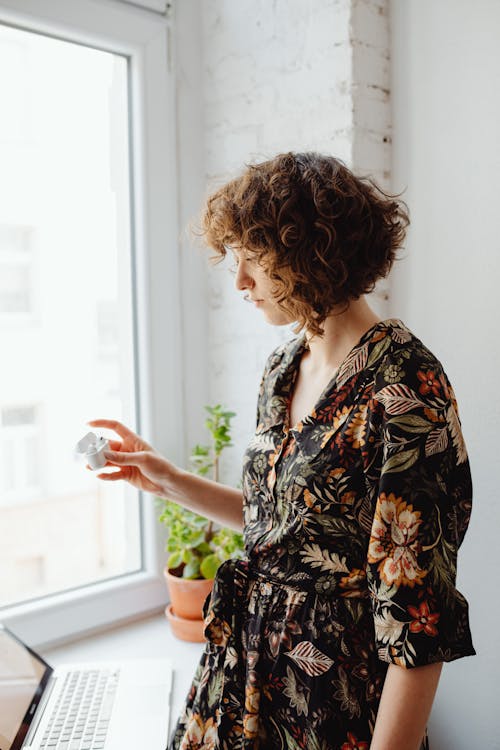 Free Photo of a Woman with Curly Hair Holding an Airpods Case  Stock Photo