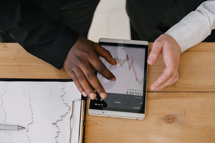 A Person Touching Screen Of A Tablet With A Graph On Screen