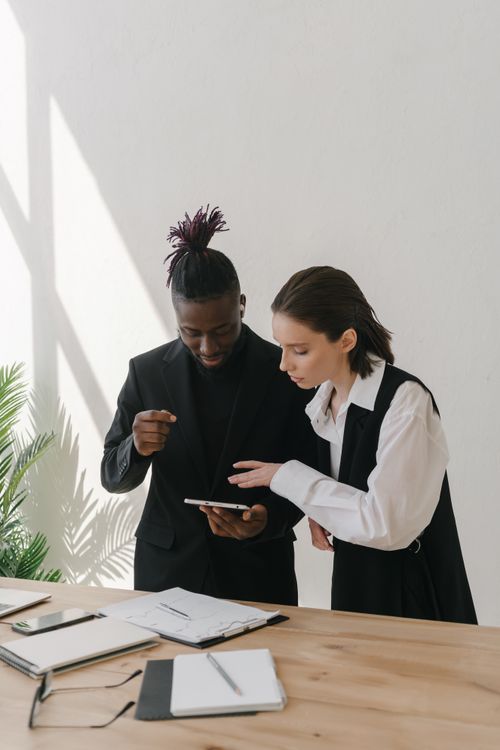 Free Black man and Caucasian woman collaborate with technology in a bright office setting. Stock Photo